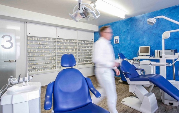 Moderne Zahnarztpraxis mit blauen Behandlungsstühlen und digitaler Ausstattung.